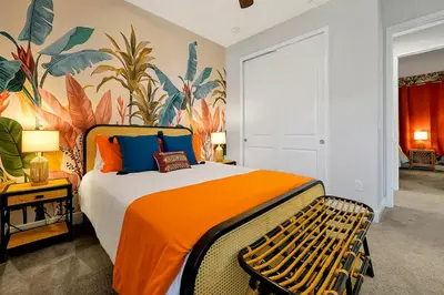 a bedroom with a large bed with an orange blanket at Family Escape | Moana Vibes | Pool + Games in Orlando
