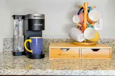 a counter top with a coffee maker and cups on it at Family Escape | Moana Vibes | Pool + Games in Orlando
