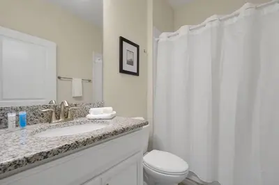 a bathroom with a sink and a toilet and a mirror at Family Pool Villa I Near Disney I 2 Free Clubhouses in Kissimmee