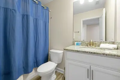 a bathroom with a toilet and a blue shower curtain at Family Pool Villa I Near Disney I 2 Free Clubhouses in Kissimmee