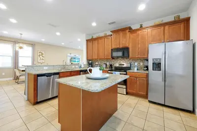 a large kitchen with wooden cabinets and stainless steel appliances at Magical Getaway Near Disney I Pool and Fun Room in Orlando