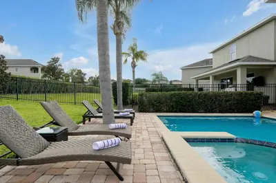 a backyard with two chairs and a swimming pool at Magical Getaway Near Disney I Pool and Fun Room in Orlando