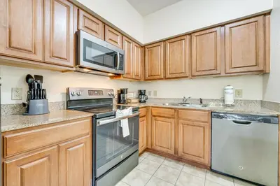 a kitchen with wooden cabinets and stainless steel appliances at Floridays Resort Condo 11 Mi to Walt Disney World! in Orlando