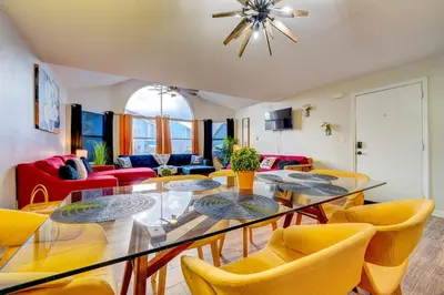 a dining room with a glass table and yellow chairs at Mickey's Cozy Condo Retreat in Kissimmee