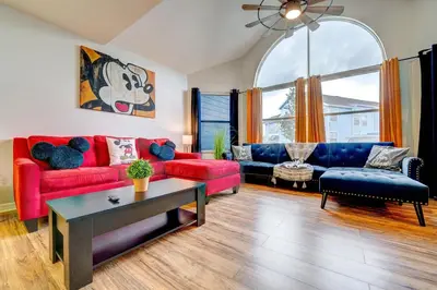 a living room with red and blue furniture and a large window at Mickey's Cozy Condo Retreat in Kissimmee