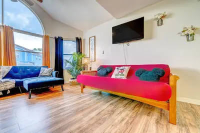 a living room with a red couch with a teddy bear on it at Mickey's Cozy Condo Retreat in Kissimmee