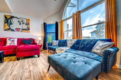 a living room with a blue couch and a window at Mickey's Cozy Condo Retreat in Kissimmee
