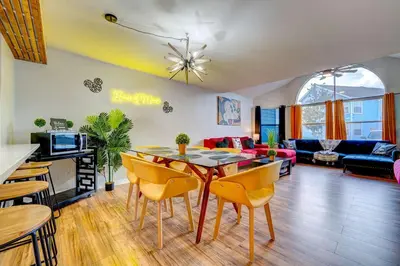 a living room with a table and yellow chairs at Mickey's Cozy Condo Retreat in Kissimmee