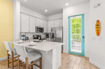 a kitchen with white cabinets and a counter with chairs at Savannah Daydreamin - For 6 in Orlando