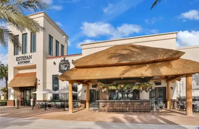 a restaurant with a large straw umbrella in front of a building at Savannah Daydreamin - For 6 in Orlando
