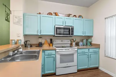 a kitchen with blue cabinets and a sink and a microwave at Magic Getaway at Emerald Island in Kissimmee
