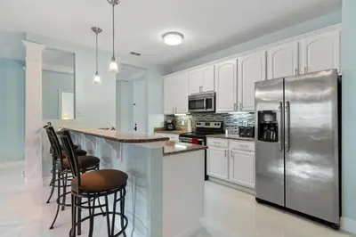 a kitchen with white cabinets and a stainless steel refrigerator at Seaescape in Orlando