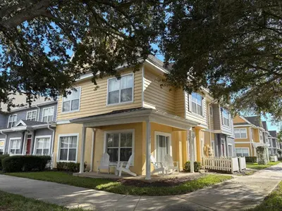 a yellow house with two chairs in front of it at 4 Bedroom 3 Bathroom Villas At Seven Dwarfs 18-108 in Kissimmee