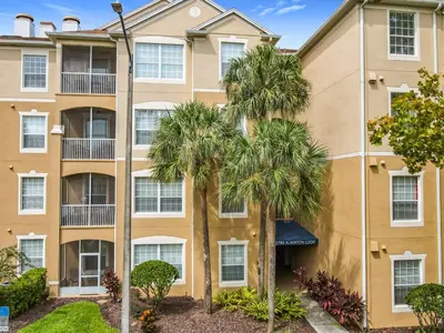 a building with palm trees in front of it at Windsor Hills Magical Condo Pool Slides By Disney in Orlando