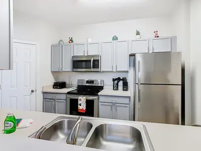 a kitchen with white cabinets and a stainless steel refrigerator at Windsor Hills Magical Condo Pool Slides By Disney in Orlando