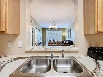 a kitchen with a sink and a living room at Windsor Hills 3BR - Mickey Themed Spacious Condo in Orlando