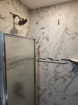 a shower in a bathroom with marble walls at Sunny Retreat in Orlando