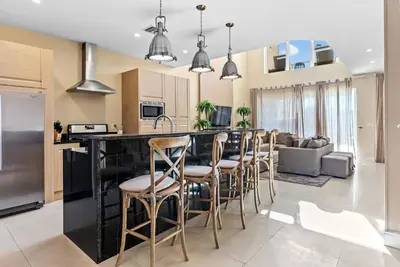 a kitchen and living room with a bar with stools at Home Luxury 03 Beds Close Disney At Magic Village in Orlando