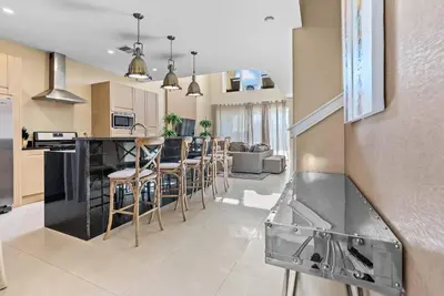 a kitchen and living room with a counter and chairs at Home Luxury 03 Beds Close Disney At Magic Village in Orlando