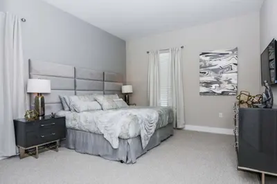 a white bedroom with a large bed and a television at Magic 5bd House 8 min from Disney in Orlando