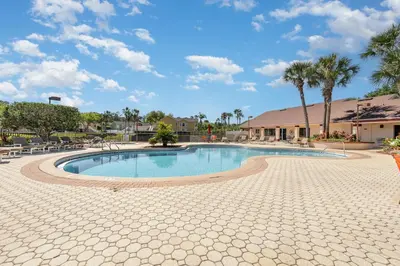 a swimming pool at a resort with chairs and trees at 8702 PAPAYA DR 2BED in Kissimmee