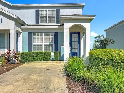 a white house with a blue door and bushes at T2531M Windsor Hills Resort 3Bedrm Private Pool in Orlando
