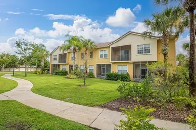 a large apartment building with palm trees and a sidewalk at OAKWATER KISSIMMEE 3 BEDS in Orlando