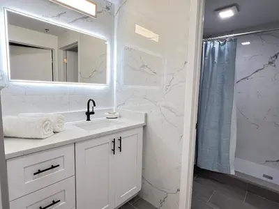 a white bathroom with a sink and a shower at Suite near Epic Universe & Universal, free parking in Orlando
