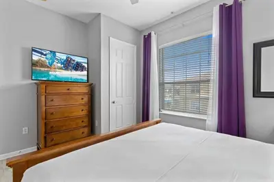 a bedroom with a bed and a dresser and a television at Amplo apê 4 quartos no Vista Cay Resort in Orlando