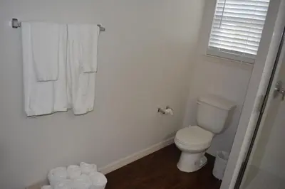 a white bathroom with a toilet and a window at Charming 4-Bedroom Townhome in Lucaya Village Near Disney in Kissimmee