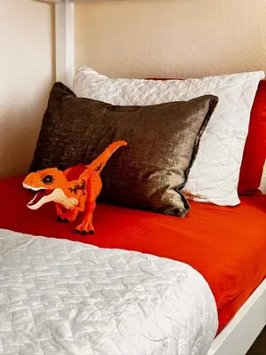 a toy dinosaur sitting on top of a bed at Modern 3BR Retreat with Comfort & Style Near Disney in Kissimmee