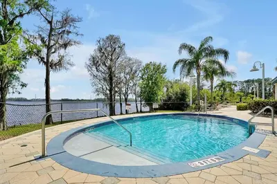a swimming pool with trees and a body of water at 13427 BLUE HERRON TOWER 1 UNIT 707 ORLANDO 1 BED in Orlando
