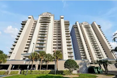 two large white buildings with palm trees in front of them at 13427 BLUE HERRON TOWER 1 UNIT 707 ORLANDO 1 BED in Orlando