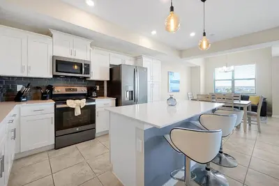 a kitchen with white cabinets and a kitchen island with bar stools at 3161 PARADOX CIRCLE UNIT 406 KISSIMMEE 2 BEDS in Kissimmee
