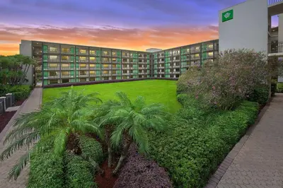a large building with palm trees in front of it at Wyndham Garden Lake Buena Vista – Disney Springs® Area in Orlando