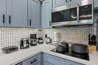 a kitchen with white cabinets and a counter top with pots and pans at Prime Location 1BR Apt Near Epic OCCC in Orlando