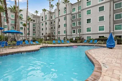 a swimming pool with blue chairs and a building at Prime Location 1BR Apt Near Epic OCCC in Orlando