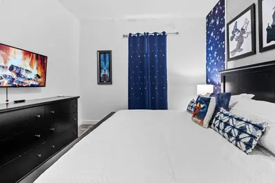 a bedroom with a large bed and a blue curtain at Home 07 Bedrooms6 Baths At Storey Lake in Kissimmee
