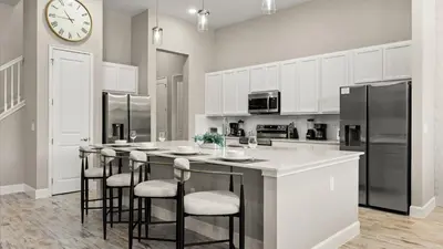 a kitchen with a large island with bar stools at Lakeside Villa with Pool BBQ Cinema & Games Room in Kissimmee