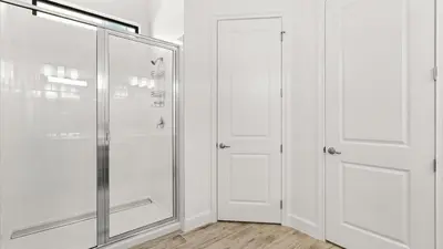a bathroom with two white closets and a glass door at Lakeside Villa with Pool BBQ Cinema & Games Room in Kissimmee