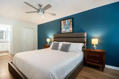 a bedroom with a large bed with a blue wall at Landing Beautiful 1BD Gym Pool in Orlando