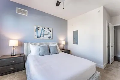 a white bedroom with a bed and two lamps at Landing Stylish 1BD Rooftop Lounge Gym in Orlando