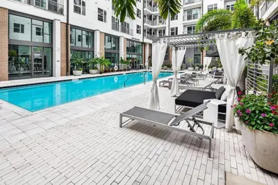 a swimming pool with a hammock next to a building at Landing Stylish 1BD Rooftop Lounge Gym in Orlando