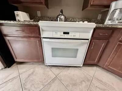 a kitchen with a white stove and brown cabinets at Entire Condo - 3Bed 2Bath- 5 mins to Disney Park in Orlando