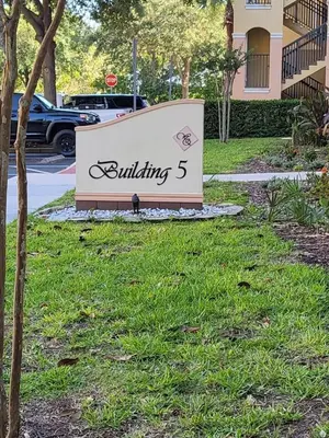 a building sign in the grass in front of a building at Entire Condo - 3Bed 2Bath- 5 mins to Disney Park in Orlando