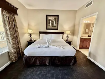 a hotel room with a large bed with white sheets at Entire Condo - 3Bed 2Bath- 5 mins to Disney Park in Orlando