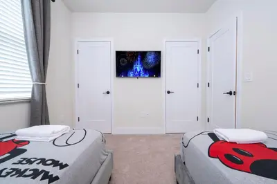 two beds in a bedroom with white walls and windows at Beautiful 4-bedroom House with Splash Pool in Orlando