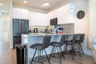 a kitchen with a bar with stools and a refrigerator at Beautiful 4-bedroom House with Splash Pool in Orlando