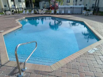 a large blue swimming pool with a metal hand rail at Great for Families 1-4 Kids! Near Disney, Universal, Shopping, Dining in Kissimmee