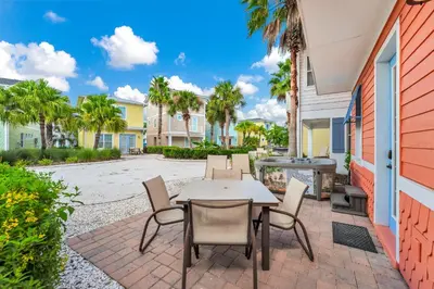 a patio with a table and chairs and a grill at Dreamy Coral Cottage With Hot Tub Near Disney With Margaritaville Resort & Island H2O Waterpark Access - 3062Pi in Orlando
